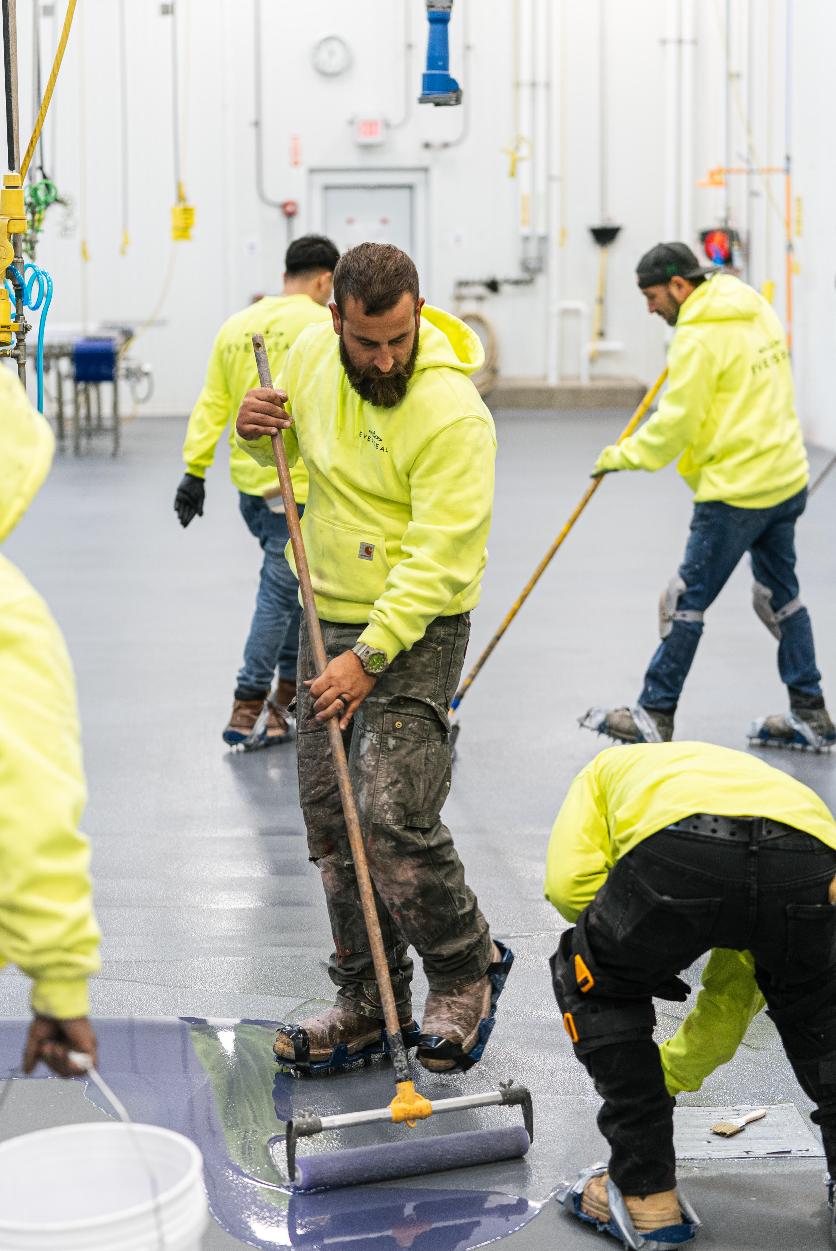 Professional FCG team of certified installers applying floor coating in industrial facility