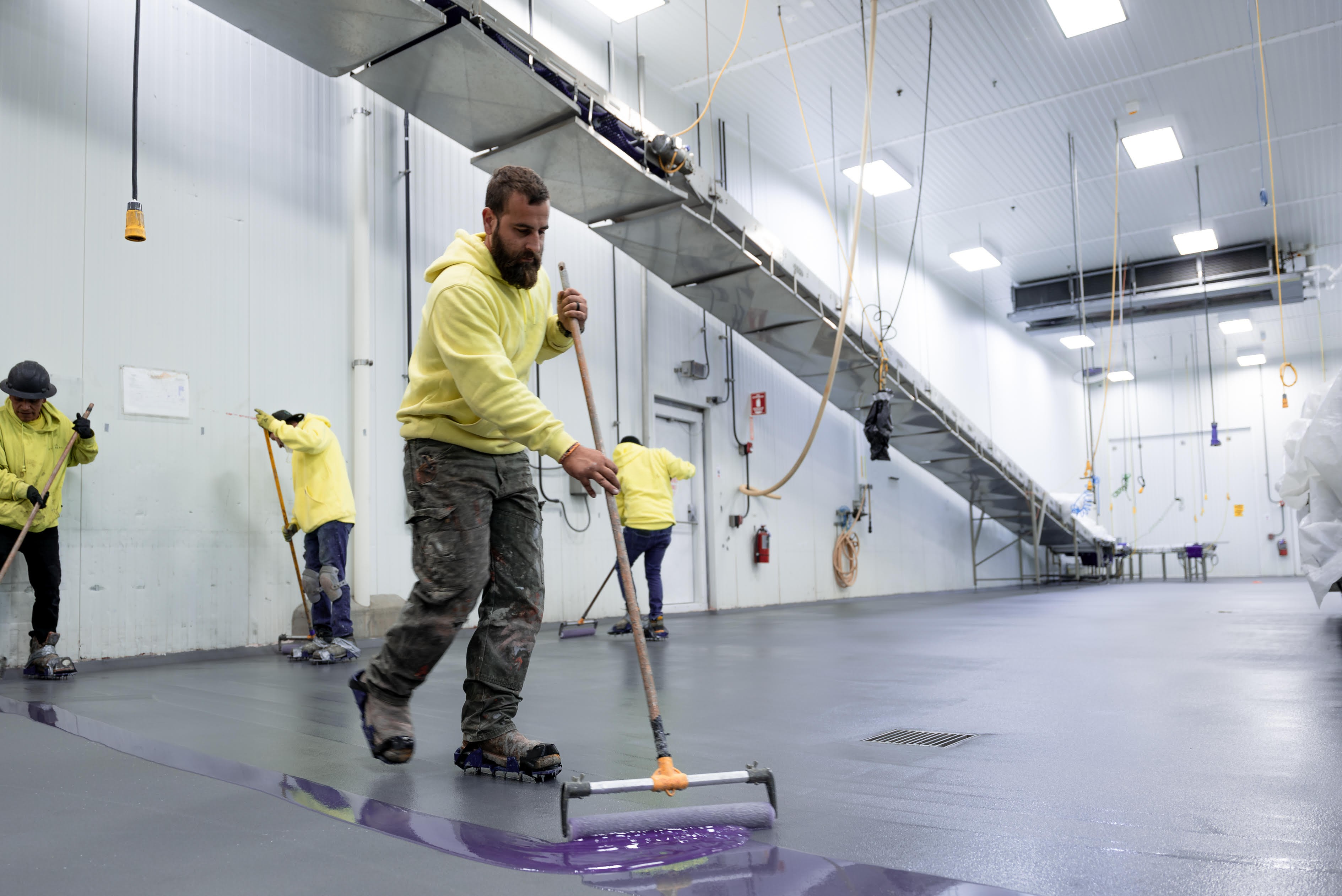 Professional floor coating crew applying industrial flooring in large facility